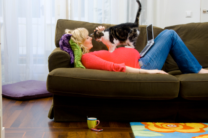 Woman lying on a couch and petting a cat